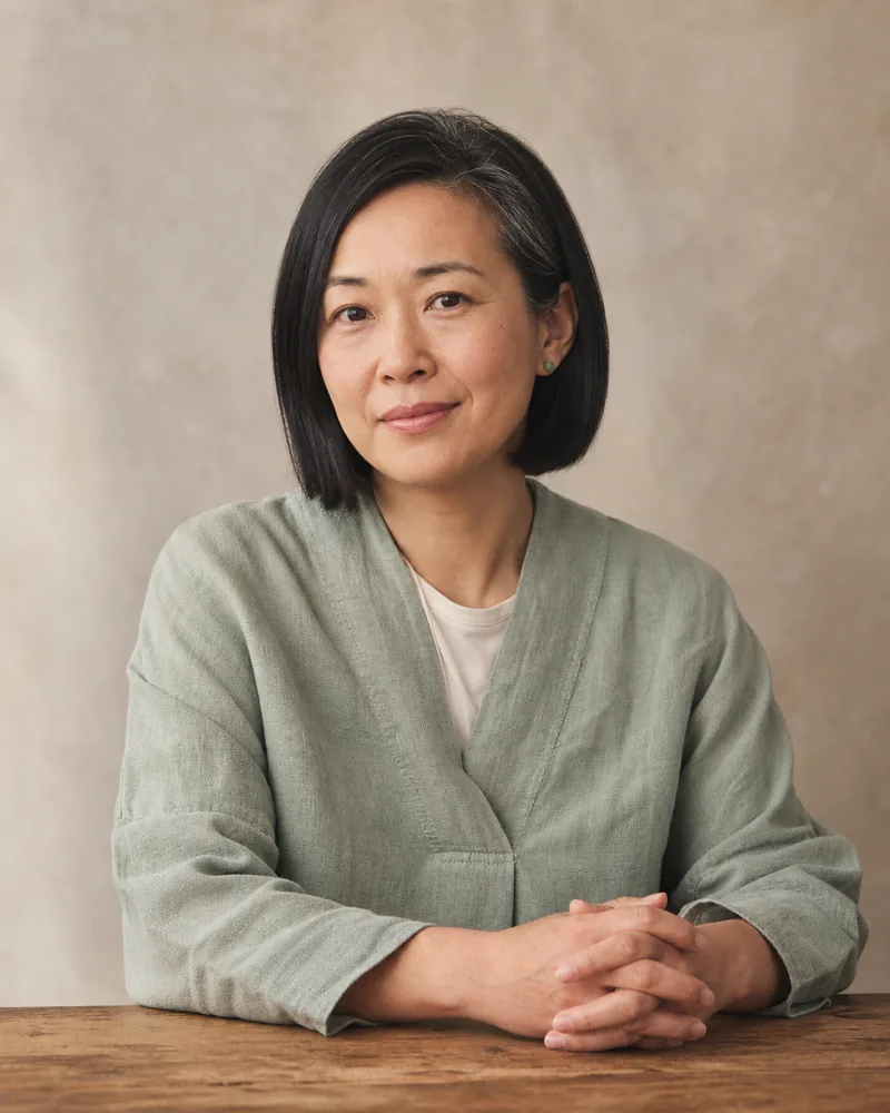 Editorial portrait of Mei-Lin Wu, a British-Chinese woman in her mid forties with chin-length straight black hair and a sage linen tunic